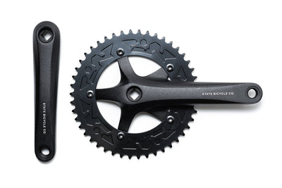 State Bicycle steel forged 3D fixed-gear crankset in black — top-down view showing 3-arm spider with geometric cutouts