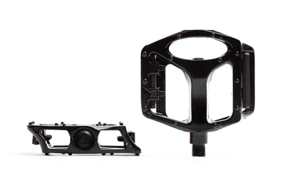 State Bicycle Co. alloy platform pedals in black, pair showing edge and face views with oval cutout windows and traction pins