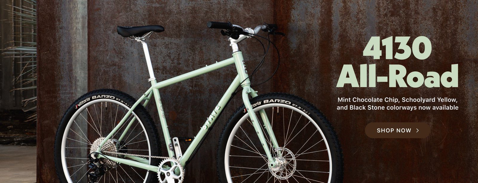 State Bicycle Co. 4130 All Road gravel bike in mint green against a rusted steel wall