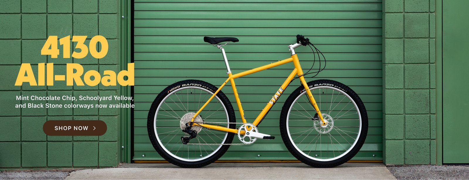 State Bicycle Co. 4130 All Road gravel bike in yellow in front of a green garage door