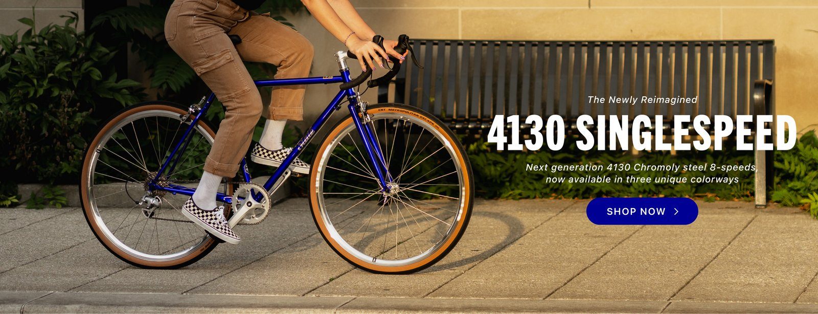 Rider on a State Bicycle Co. 4130 Road in sapphire blue on a city sidewalk